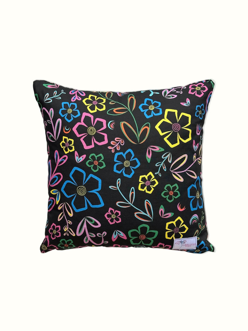 A square throw pillow with a black background and a vibrant, multicolored floral pattern, shown against a plain off-white background.